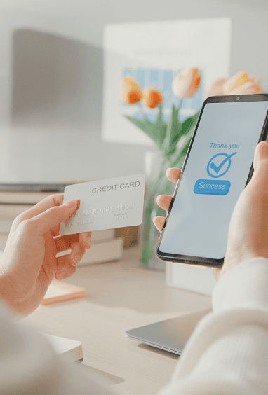 Woman at home using a phone and credit card to shop online